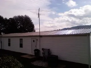 New metal roof on a single wide mobile home with a TV antenna in Hollis Center