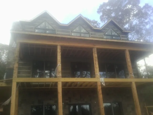 Dormers and porch framing on a large log home under construction — Roof Coating work by our crew in Hollis Center
