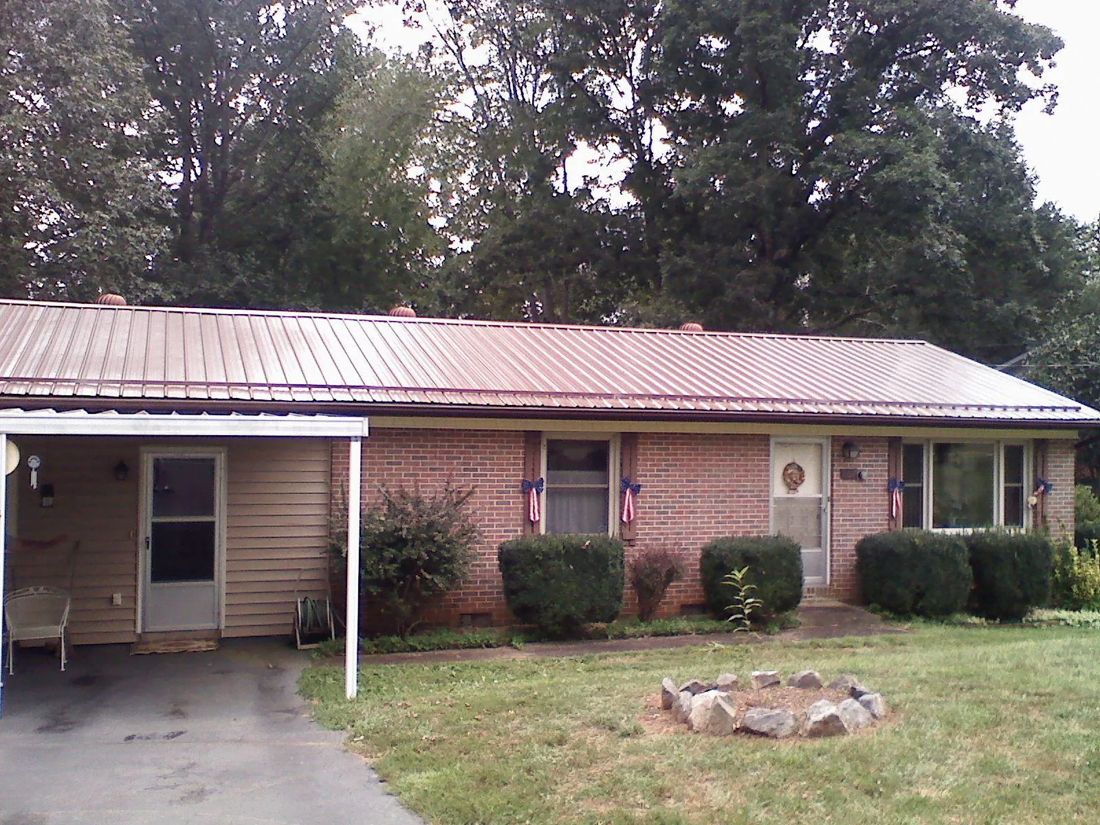Bronze metal roof and carport on a brick ranch home — Roof Repair work by our crew in Hollis Center