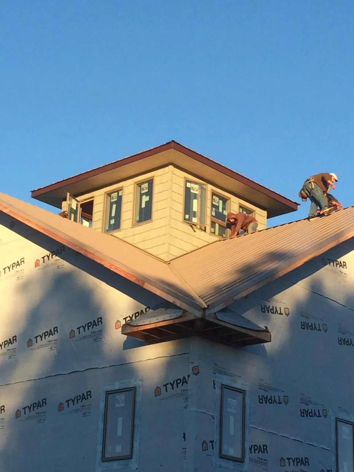 Roofers working around a rooftop cupola on a new metal roof at sunset — Roof Waterproofing in Hollis Center by Roofing Brothers